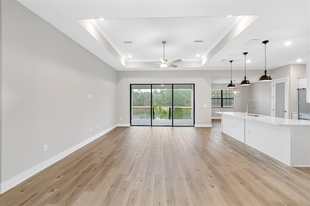 4799 Hickory Oak Loop, Brooksville, FL 34601 - unfurnished living room featuring crown molding, a tray ceiling, light wood-style floors, ceiling fan, and baseboards