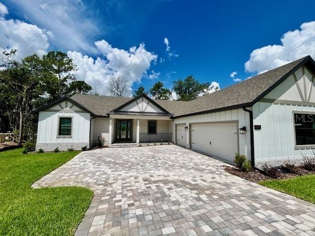 4799 Hickory Oak Loop, Brooksville, FL 34601 - view of front of house featuring decorative driveway, a garage, a front yard, covered porch, and board and batten siding
