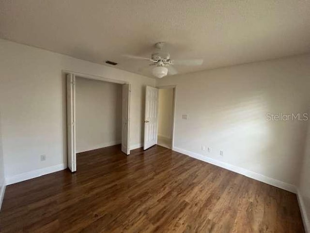 2635 Jarvis Cir, Palm Harbor, FL 34683 - unfurnished bedroom with a closet, dark wood-style floors, baseboards, and a ceiling fan