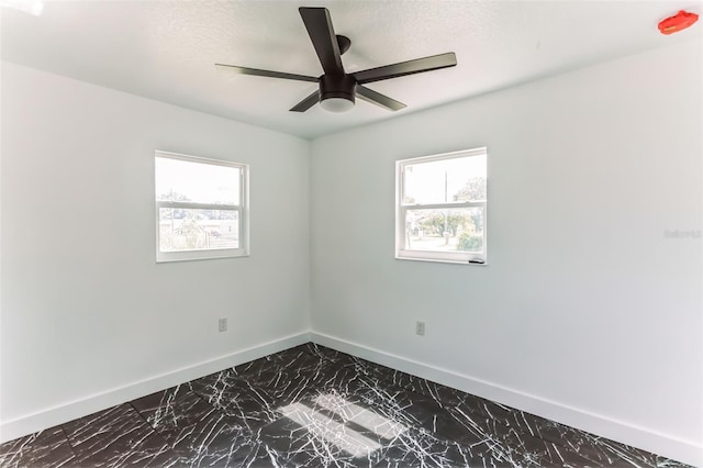 2010 4th Ave W, Palmetto, FL 34221 - empty room featuring dark marble finish floors, healthy amount of natural light, baseboards, a ceiling fan, and a textured ceiling