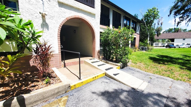 230 N Bayshore Blvd Unit 103, Clearwater, FL 33759 - view of exterior entry with stucco siding, a lawn, and central AC