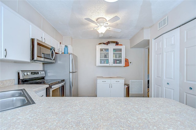 1655 S Highland Ave Unit B118, Clearwater, FL 33756 - kitchen featuring appliances with stainless steel finishes, light countertops, ceiling fan, white cabinetry, and glass insert cabinets
