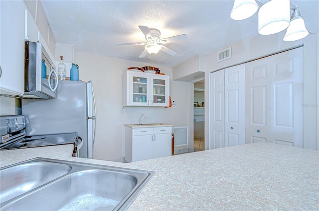 1655 S Highland Ave Unit B118, Clearwater, FL 33756 - kitchen featuring stainless steel appliances, ceiling fan, light countertops, glass insert cabinets, and white cabinetry