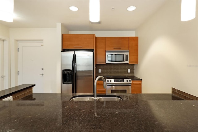 400 4th Ave S Unit 301, Saint Petersburg, FL 33701 - kitchen with appliances with stainless steel finishes, a sink, brown cabinetry, backsplash, and dark stone countertops