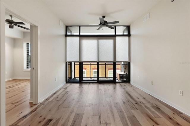 400 4th Ave S Unit 301, Saint Petersburg, FL 33701 - unfurnished room with ceiling fan, wood finished floors, baseboards, a high ceiling, and a wall of windows