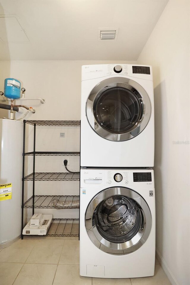 400 4th Ave S Unit 301, Saint Petersburg, FL 33701 - laundry room featuring stacked washer / dryer, gas water heater, light tile patterned flooring, and baseboards