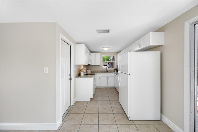 10599 111th Ave N, Largo, FL 33773 - kitchen with freestanding refrigerator, electric range oven, light tile patterned floors, white cabinetry, and light countertops