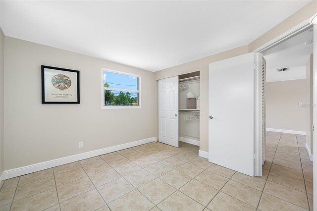 10599 111th Ave N, Largo, FL 33773 - unfurnished bedroom featuring light tile patterned floors, baseboards, and a closet