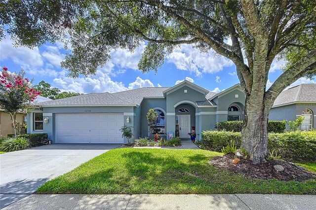 4315 Whittner Dr, Land O Lakes, FL 34639 - view of front of house with stucco siding, an attached garage, a front yard, and concrete driveway