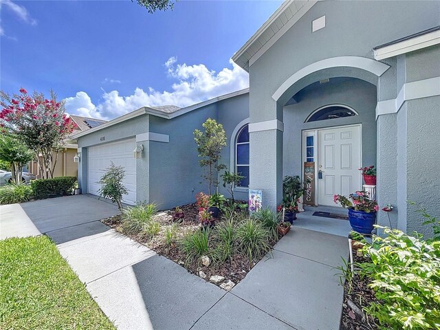 4315 Whittner Dr, Land O Lakes, FL 34639 - entrance to property featuring stucco siding, a garage, and concrete driveway