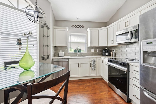 5143 Lochmead Ter, Zephyrhills, FL 33541 - kitchen featuring appliances with stainless steel finishes, decorative backsplash, white cabinetry, a sink, and dark wood finished floors