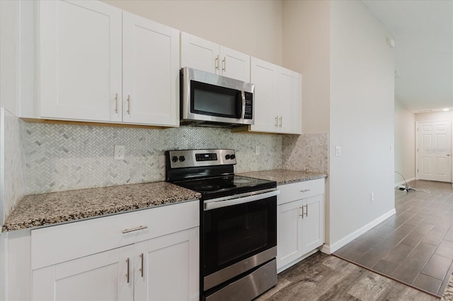 13016 Boggy Creek Dr, Riverview, FL 33579 - kitchen featuring stainless steel appliances, light stone counters, tasteful backsplash, dark wood finished floors, and white cabinetry