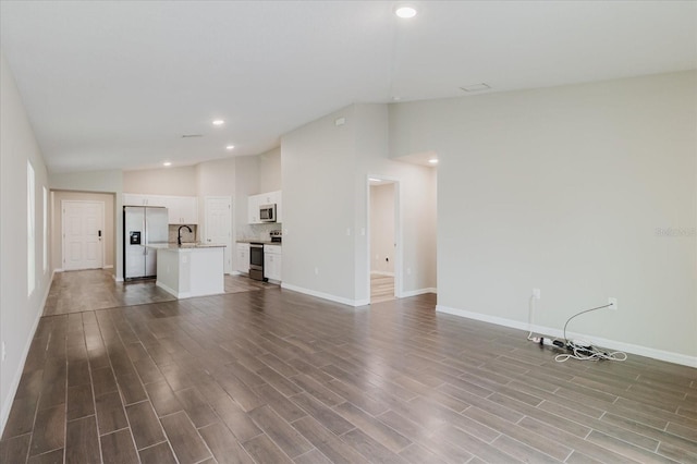 13016 Boggy Creek Dr, Riverview, FL 33579 - unfurnished living room with vaulted ceiling, baseboards, a sink, dark wood-style floors, and recessed lighting