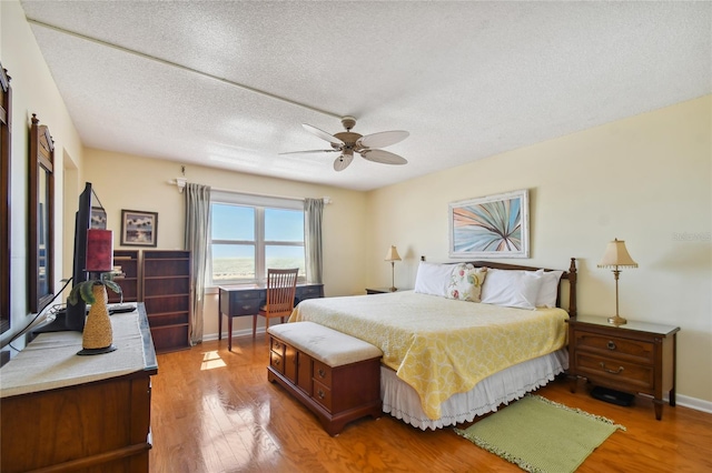 11000 Gulf Blvd Unit 703, Treasure Island, FL 33706 - bedroom with light wood-style flooring, a textured ceiling, and a ceiling fan