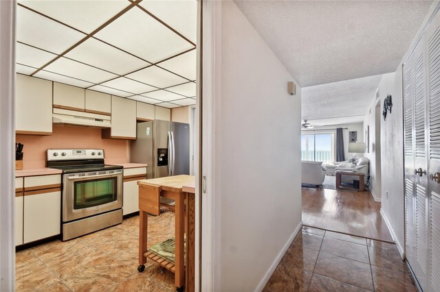 11000 Gulf Blvd Unit 703, Treasure Island, FL 33706 - kitchen featuring appliances with stainless steel finishes, under cabinet range hood, baseboards, and light tile patterned flooring