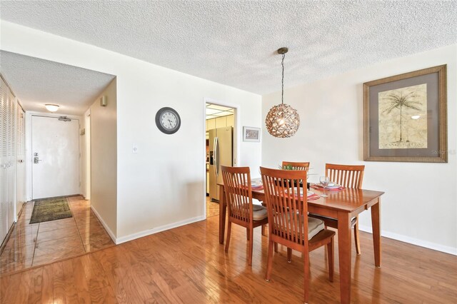 11000 Gulf Blvd Unit 703, Treasure Island, FL 33706 - dining space featuring a textured ceiling, wood finished floors, a chandelier, and baseboards