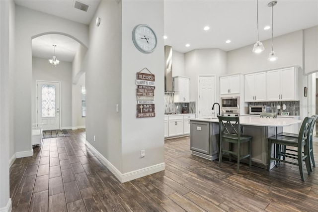 808 Vittorio Pl, Brandon, FL 33511 - kitchen with stainless steel appliances, a high ceiling, a center island with sink, dark wood-type flooring, and arched walkways