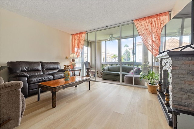 19029 US Highway 19 N Unit 3-1, Clearwater, FL 33764 - living area with floor to ceiling windows, wood finished floors, a fireplace with raised hearth, a textured ceiling, and a ceiling fan