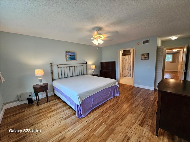 2221 Norwegian Dr Unit 15, Clearwater, FL 33763 - bedroom with wood finished floors, a textured ceiling, baseboards, connected bathroom, and a ceiling fan