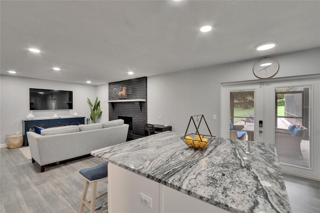 8222 Valrie Ln, Riverview, FL 33569 - kitchen with light wood finished floors, french doors, light stone counters, a fireplace, and recessed lighting
