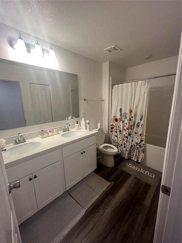 4743 Deer Track St, Tampa, FL 33610 - bathroom featuring wood finished floors, toilet, double vanity, shower / tub combo, and a textured ceiling