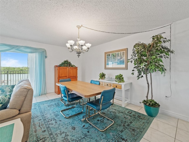 18610 Gulf Blvd Unit 208, Indian Shores, FL 33785 - dining space featuring a chandelier, light tile patterned floors, a textured ceiling, a water view, and baseboards