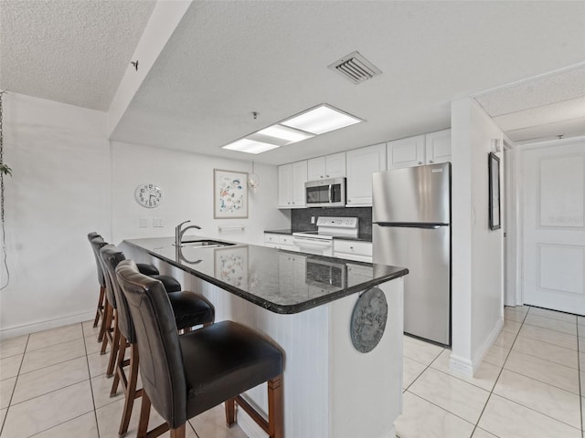 18610 Gulf Blvd Unit 208, Indian Shores, FL 33785 - kitchen with stainless steel appliances, a sink, light tile patterned flooring, a peninsula, and a textured ceiling