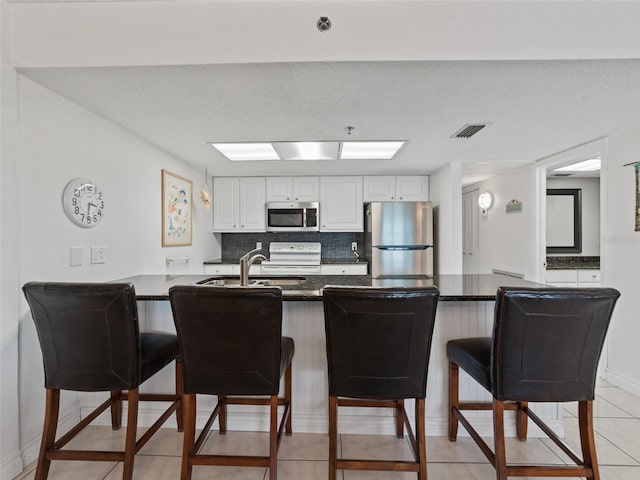 18610 Gulf Blvd Unit 208, Indian Shores, FL 33785 - kitchen featuring appliances with stainless steel finishes, a sink, a peninsula, a breakfast bar, and white cabinets