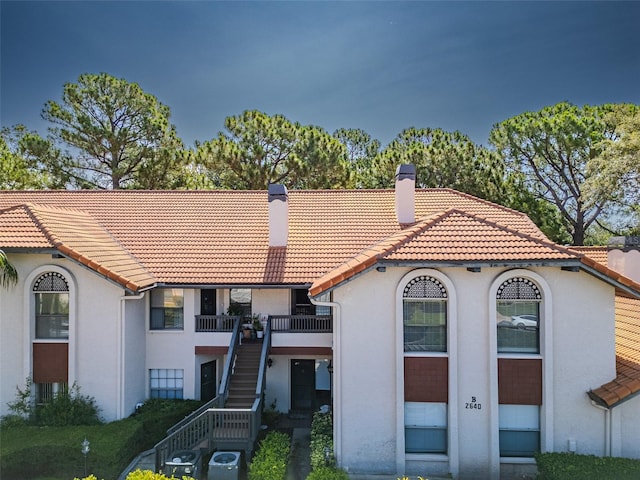 2640 Enterprise Rd E Unit B25, Clearwater, FL 33759 - mediterranean / spanish-style house with a tiled roof, stucco siding, a chimney, and stairs