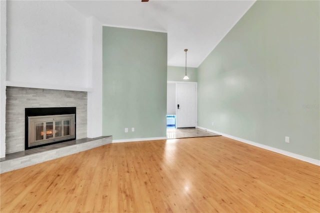 2640 Enterprise Rd E Unit B25, Clearwater, FL 33759 - unfurnished living room with wood finished floors, baseboards, a glass covered fireplace, and high vaulted ceiling