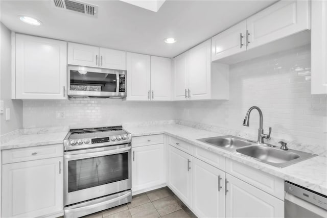 2640 Enterprise Rd E Unit B25, Clearwater, FL 33759 - kitchen featuring appliances with stainless steel finishes, a sink, tasteful backsplash, white cabinets, and recessed lighting
