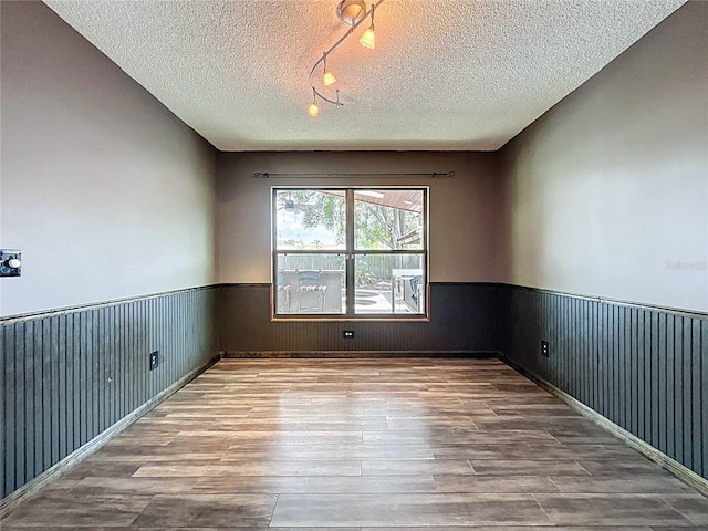 11525 Country Oaks Dr, Tampa, FL 33618 - empty room with wood finished floors, wainscoting, track lighting, and a textured ceiling