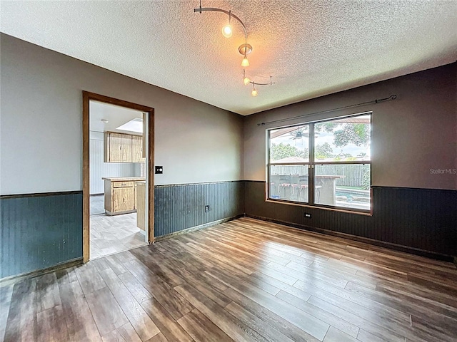 11525 Country Oaks Dr, Tampa, FL 33618 - empty room with wainscoting, wood finished floors, a textured ceiling, and wood walls