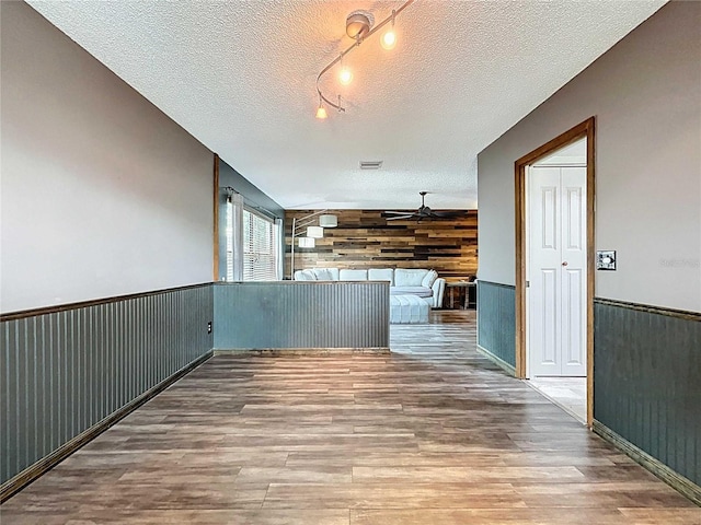 11525 Country Oaks Dr, Tampa, FL 33618 - hall featuring wood walls, wood finished floors, a wainscoted wall, rail lighting, and a textured ceiling