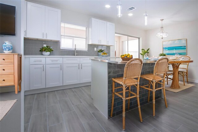 1906 Canterbury Ln Unit 20, Sun City Center, FL 33573 - kitchen with white cabinetry, tasteful backsplash, light wood-style floors, light countertops, and hanging light fixtures