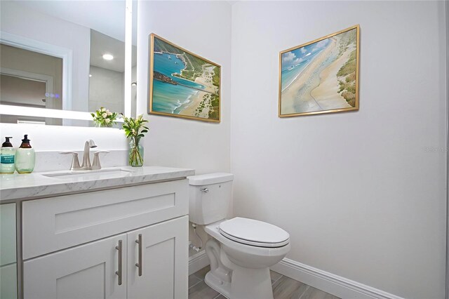 1906 Canterbury Ln Unit 20, Sun City Center, FL 33573 - half bathroom featuring baseboards, toilet, vanity, and wood finished floors