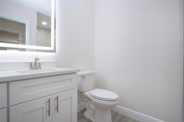 1906 Canterbury Ln Unit 20, Sun City Center, FL 33573 - bathroom featuring baseboards, toilet, vanity, and wood finished floors