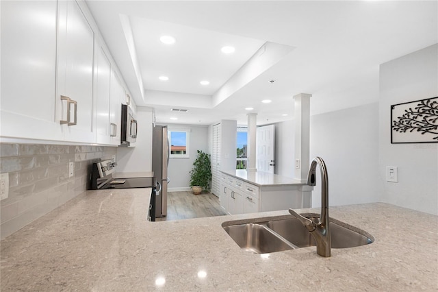 9461 Harbor Greens Way Unit 502, Seminole, FL 33776 - kitchen featuring stainless steel appliances, a sink, light stone countertops, tasteful backsplash, and white cabinetry