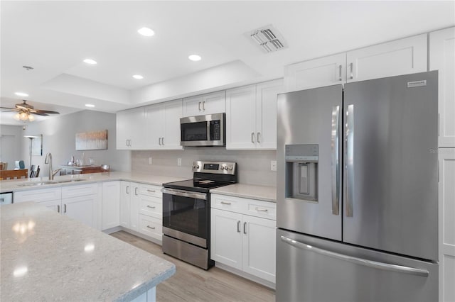 9461 Harbor Greens Way Unit 502, Seminole, FL 33776 - kitchen featuring stainless steel appliances, a sink, a tray ceiling, light wood-style floors, and white cabinets
