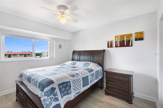 9461 Harbor Greens Way Unit 502, Seminole, FL 33776 - bedroom featuring light wood-style floors, baseboards, a ceiling fan, and a textured ceiling