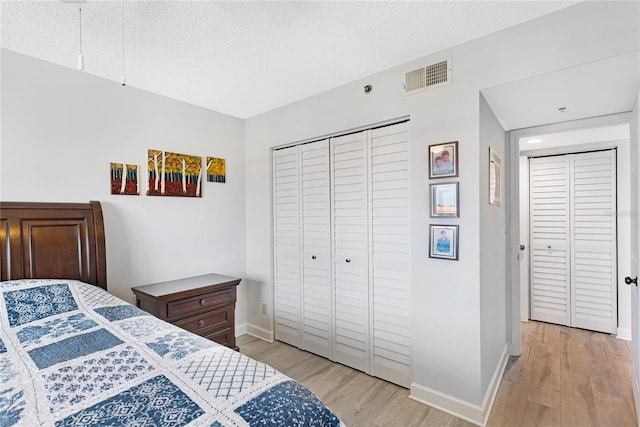 9461 Harbor Greens Way Unit 502, Seminole, FL 33776 - bedroom featuring light wood finished floors, baseboards, a closet, and a textured ceiling
