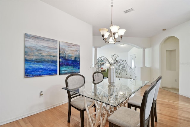 19409 Weymouth Dr, Land O Lakes, FL 34638 - dining room with light wood finished floors, arched walkways, decorative columns, and a chandelier