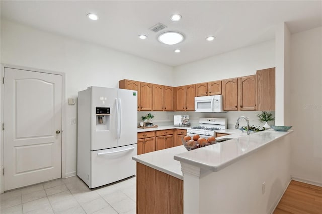 19409 Weymouth Dr, Land O Lakes, FL 34638 - kitchen featuring white appliances, light countertops, a sink, a peninsula, and brown cabinets
