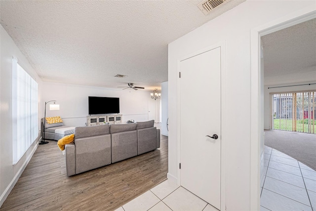 13013 Sawmill Way, Hudson, FL 34667 - living room with a textured ceiling, a ceiling fan, healthy amount of natural light, light tile patterned floors, and baseboards