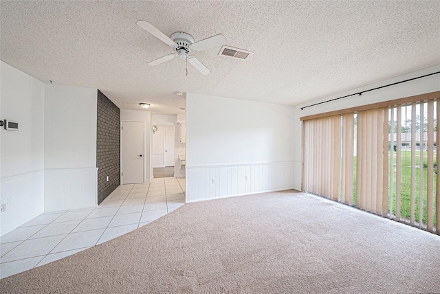 13013 Sawmill Way, Hudson, FL 34667 - carpeted empty room featuring a ceiling fan, tile patterned floors, a wainscoted wall, and a textured ceiling