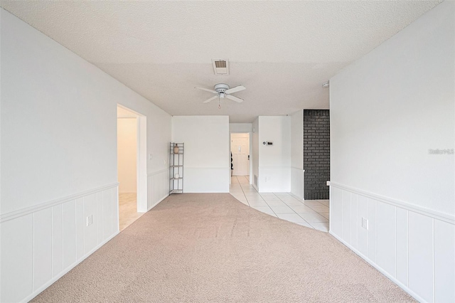 13013 Sawmill Way, Hudson, FL 34667 - empty room featuring a ceiling fan, light colored carpet, wainscoting, light tile patterned floors, and a textured ceiling