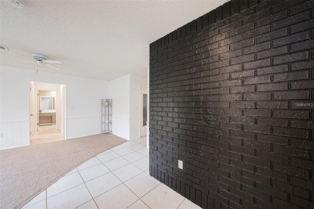 13013 Sawmill Way, Hudson, FL 34667 - spare room with light tile patterned floors, ceiling fan, a textured ceiling, light colored carpet, and wainscoting