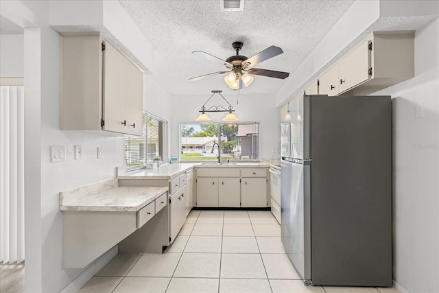 13013 Sawmill Way, Hudson, FL 34667 - kitchen with freestanding refrigerator, light countertops, a textured ceiling, ceiling fan, and light tile patterned floors