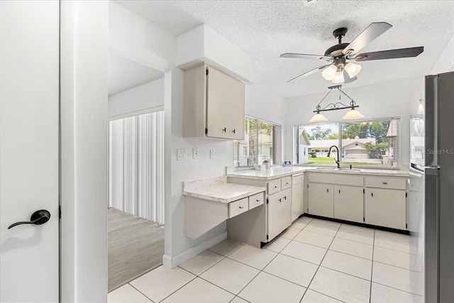 13013 Sawmill Way, Hudson, FL 34667 - kitchen featuring a sink, light countertops, freestanding refrigerator, light tile patterned flooring, and a textured ceiling