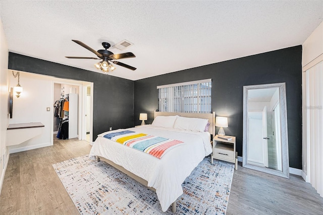 13013 Sawmill Way, Hudson, FL 34667 - bedroom with light wood-type flooring, baseboards, a closet, a walk in closet, and ceiling fan